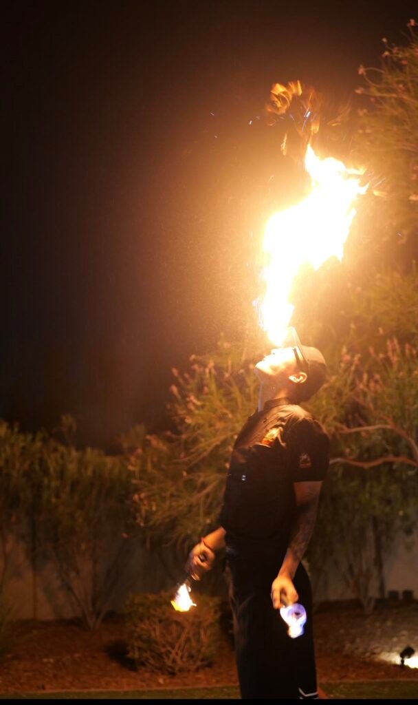 Hibachi chef performing a fire-breathing trick at night