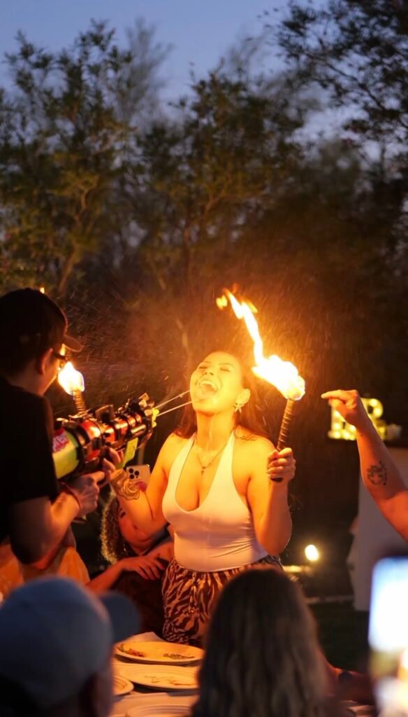 Guest holding a flaming torch while friends cheer at a backyard hibachi party
