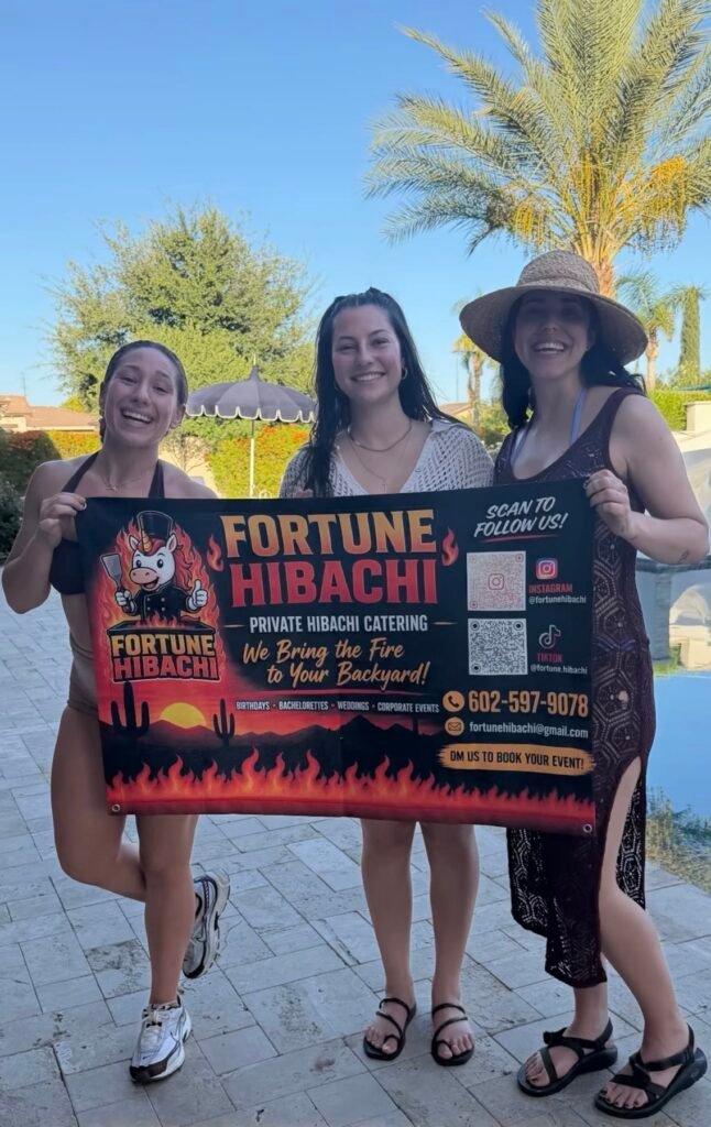 Guests holding a Fortune Hibachi banner at an outdoor reunion party