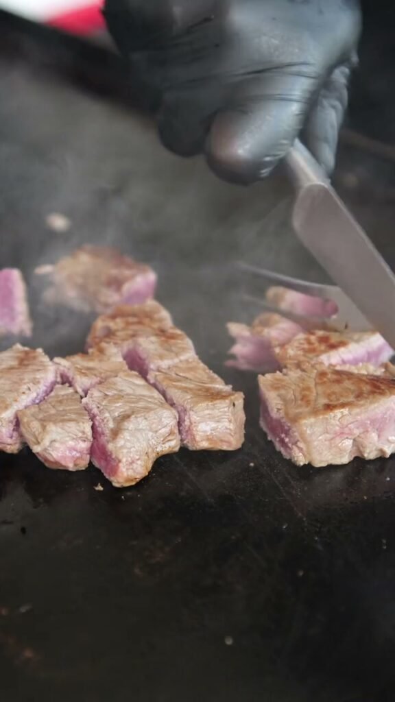 Steak searing on the hibachi grill next to fried rice