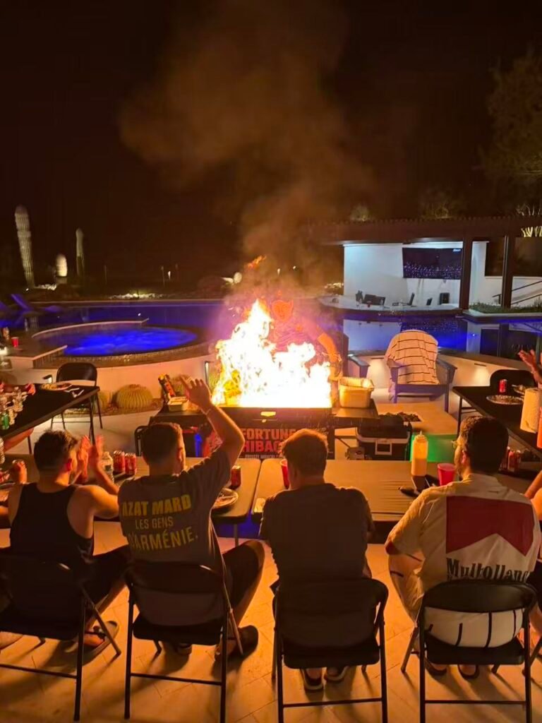 Guests watching a hibachi fire show beside a backyard pool