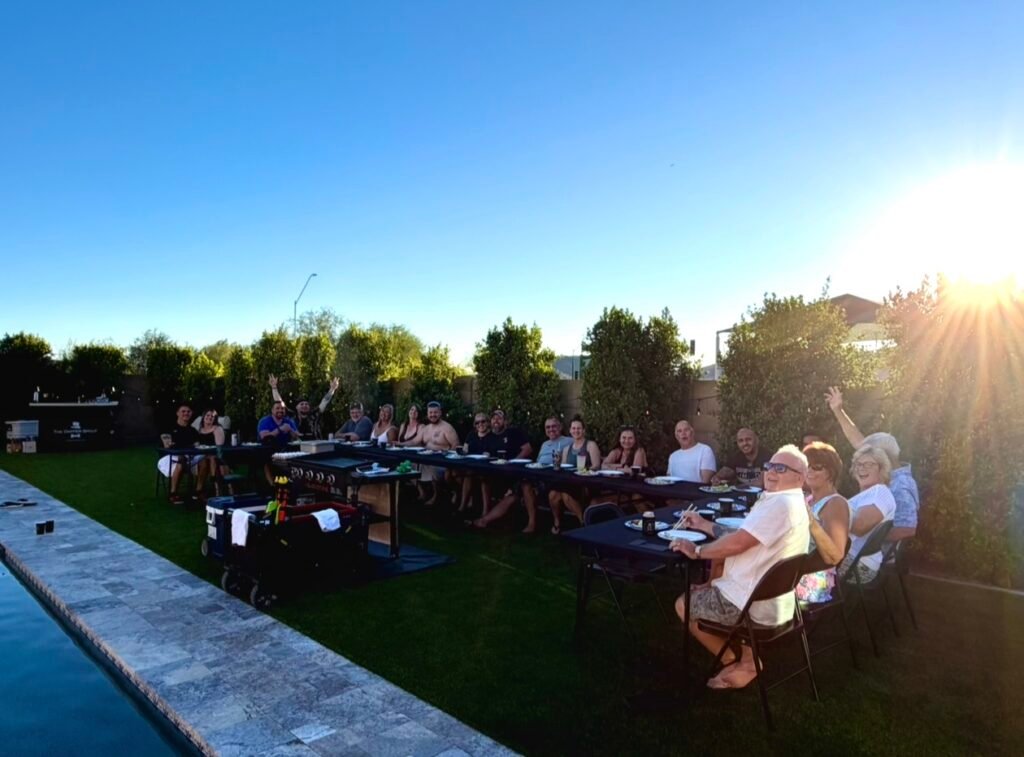 Guests gathered around a Fortune Hibachi grill at a backyard dinner party beside a pool at sunset
